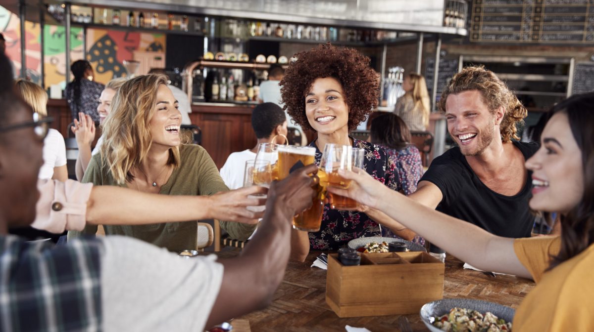 Group Of Young Friends Meeting For Drinks And Food Making A Toast In Restaurant