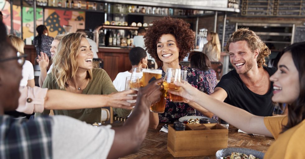 Group Of Young Friends Meeting For Drinks And Food Making A Toast In Restaurant